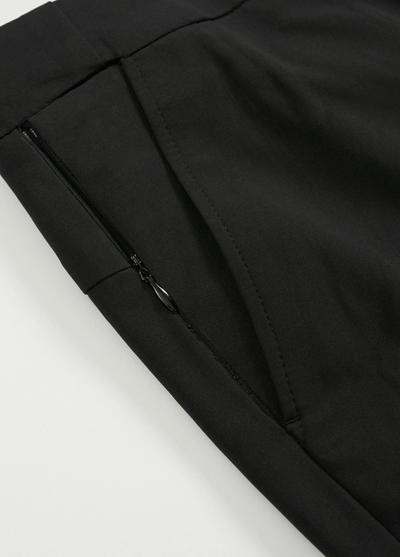 a close-up of the zippered side pocket of men's black golf pants