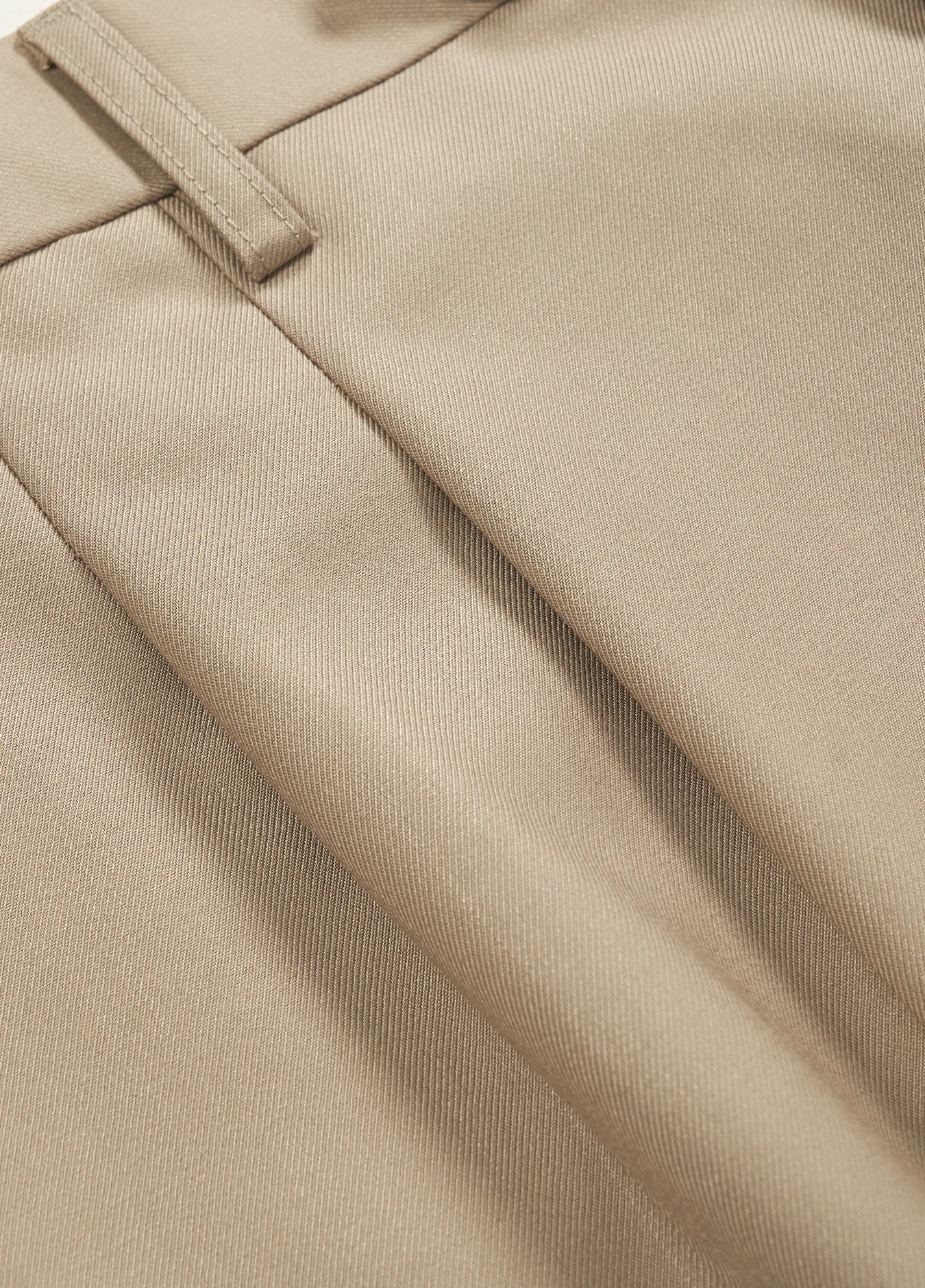 a close-up of the double pleats on mens khaki dress pants