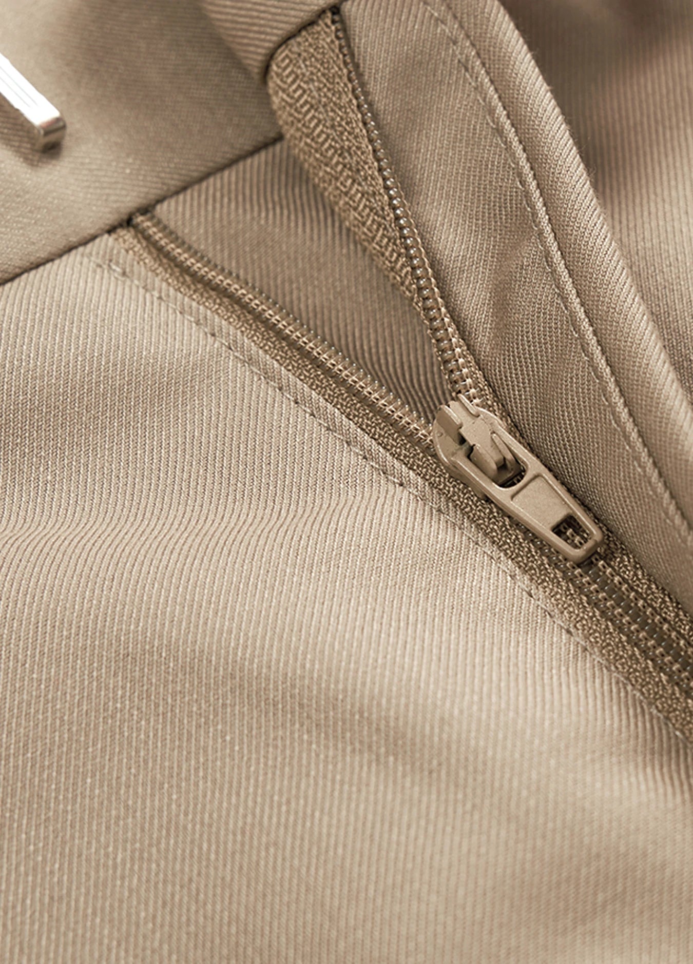 A close-up of the zipper of men's khaki dress pants